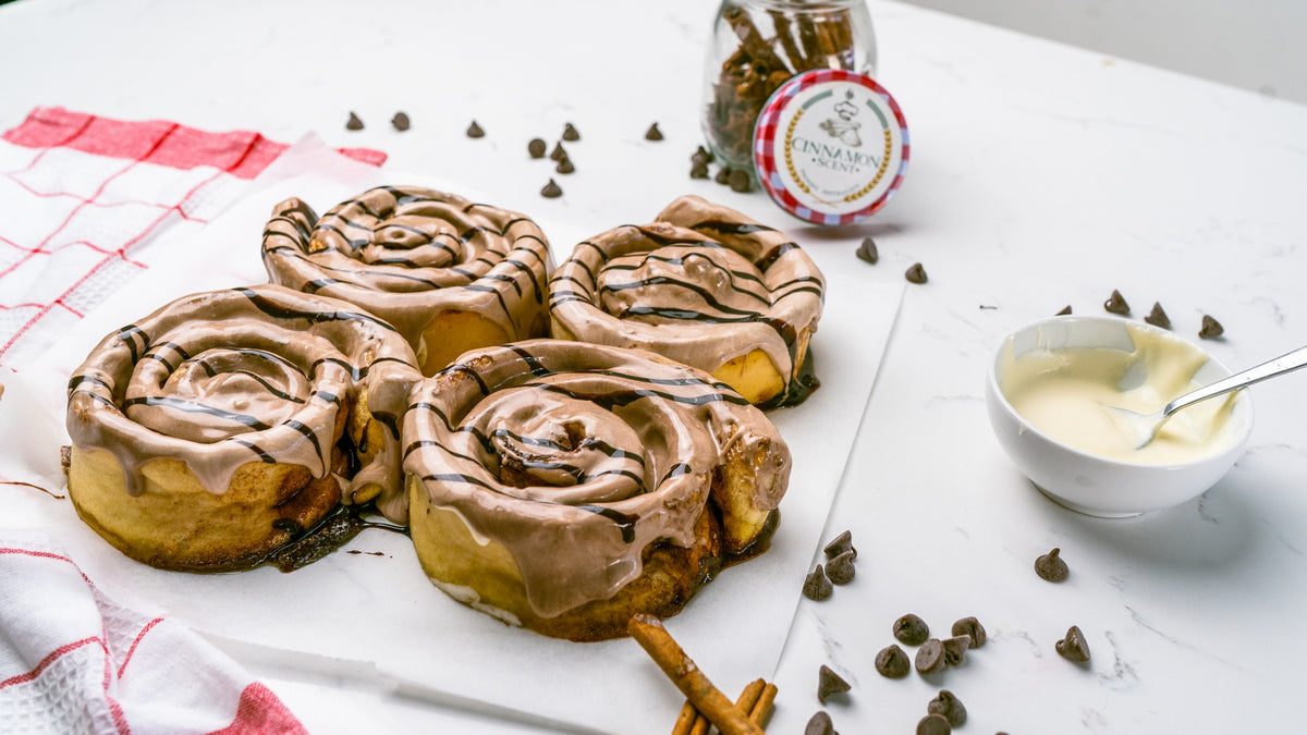 Chocolate-drizzled cinnamon scrolls with a bowl of icing