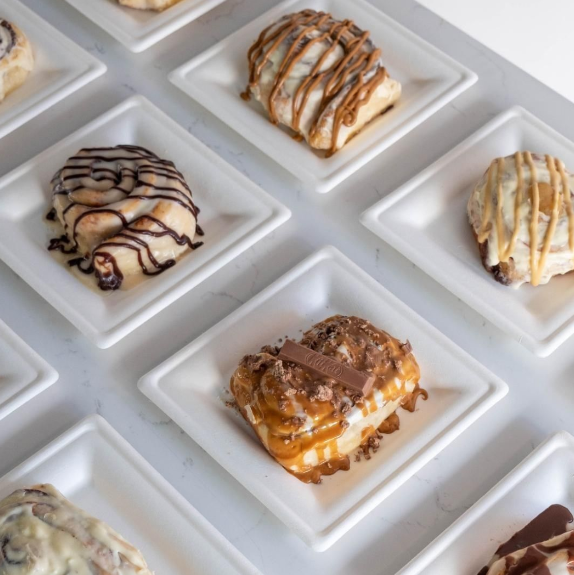 Assorted cinnabites with chocolate and caramel toppings on white plates